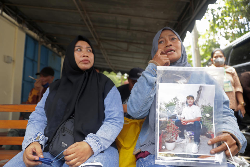 Rini Hanifah, holds a picture of her son Agus Riyansah who was a victim in the October deadly crowd surge, as she waits outside a court building in Surabaya, East Java, Indonesia, Monday, Jan, 16, 2023. An Indonesian court began trial Monday against five men on charges of negligence leading to deaths of 135 people after police fired tear gas inside a soccer stadium, setting off a panicked run for the exits in which many were crushed. (AP Photo/Trisnadi)