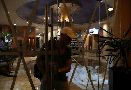 A man leaves a hotel with taped-up glass panels to protect against the expected severe winds of Hurricane Willa as it approaches the Pacific beach resort of Mazatlan, Mexico October 22, 2018. REUTERS/Henry Romero