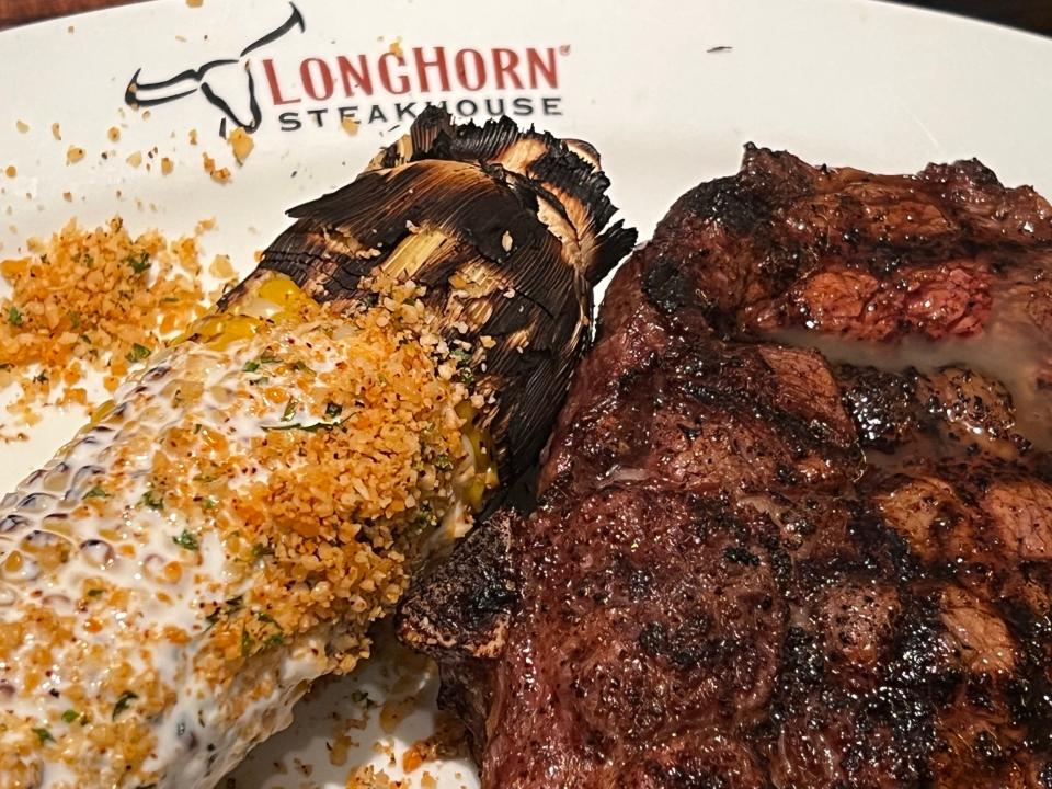 A Longhorn Steakhouse bone-in ribeye with a side of corn on the cob