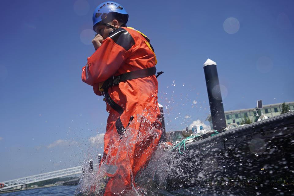 Lucas Drake jumps in the water with other classmates during a Global Wind Organisation certification class at the Massachusetts Maritime Academy in Bourne, Mass., Thursday, Aug. 4, 2022. At the 131-year-old maritime academy along Buzzards Bay, people who will build the nation's first commercial-scale offshore wind farm are learning the skills to stay safe while working around turbines at sea. (AP Photo/Seth Wenig)