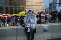 A protester in rain coat wears a sign which reads "Protect Hong Kong" during a march in Hong Kong on Sunday, Aug. 18, 2019. Heavy rain fell on tens of thousands of umbrella-toting protesters Sunday as they marched from a packed park and filled a major road in Hong Kong, where mass pro-democracy demonstrations have become a regular weekend activity over the summer. (AP Photo/Kin Cheung)