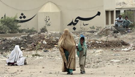 An internally displaced woman walks outside a food distribution centre set up in a sports stadium in Bannu, in northwest Pakistan July 25, 2014. REUTERS/Caren Firouz