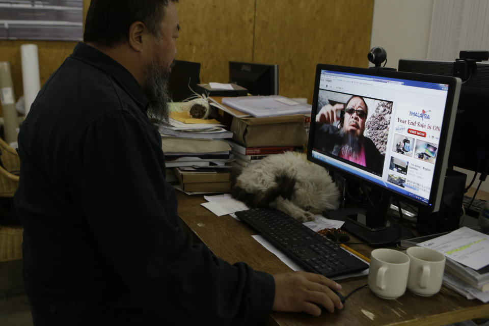 Chinese dissident artist Ai Weiwei plays a video clip he uploaded on Youtube on a computer in Beijing, China, Thursday, Oct. 25, 2012. In the video, Ai sports a neon-pink T-shirt, black jacket and dark sunglasses and energetically mimics rodeo-style dance moves made famous by South Korean rapper PSY whose original video became an Internet sensation. (AP Photo/Ng Han Guan)