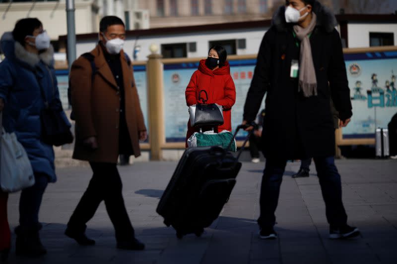People wearing face masks walks outside Beijing Railway Station as the country is hit by an outbreak of the new coronavirus, in Beijing