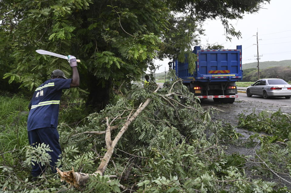 Trabajadores retiran el jueves 4 de julio de 2024 ramas de árboles que fueron derribados por el huracán Beryl, en Kingston, Jamaica. (AP Foto/Collin Reid)