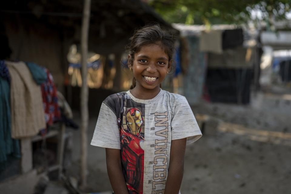 Garima, 10, poses for a portrait outside her makeshift home on the flood plain of Yamuna River after coming from school in New Delhi, India, Friday, Sept. 29, 2023. (AP Photo/Altaf Qadri)