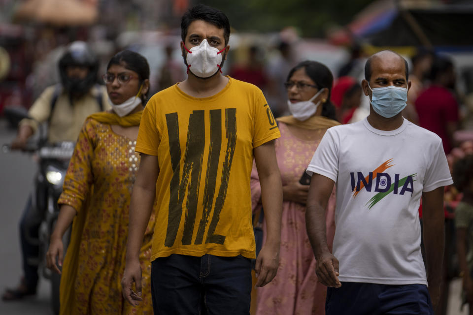 People wearing masks as a precaution against the coronavirus walk through a market in New Delhi, India, Thursday, Aug. 11, 2022. The Indian capital reintroduced public mask mandates on Thursday as COVID-19 cases continue to rise across the country. (AP Photo/Altaf Qadri)