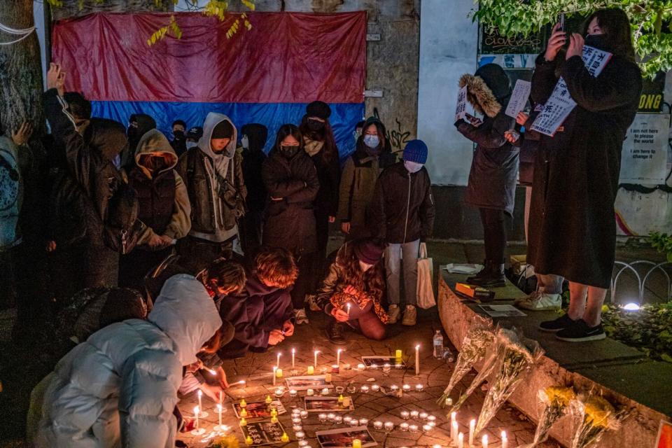 Demonstrators gather around candles on the ground during a vigil.