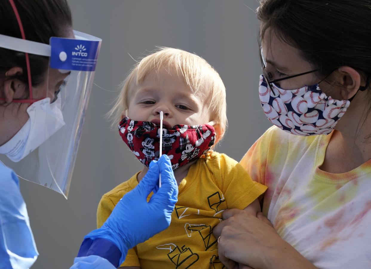 One-year-old Quentin Brown is held by his mother, Heather Brown, as he eyes a swab while being tested for COVID-19 at a new walk-up testing site at Chief Sealth High School on Friday, Aug. 28, 2020, in Seattle, Wash. The child's daycare facility requires testing for the virus. The coronavirus testing site is the fourth now open by the city and is free.