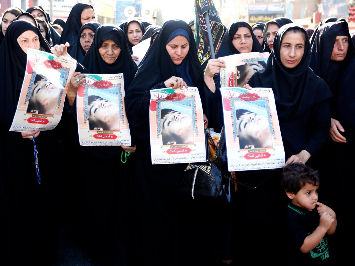 Iranian women hold pictures of a child who was killed in Saturday's attack during a funeral ceremony in Ahvaz yesterday: EPA