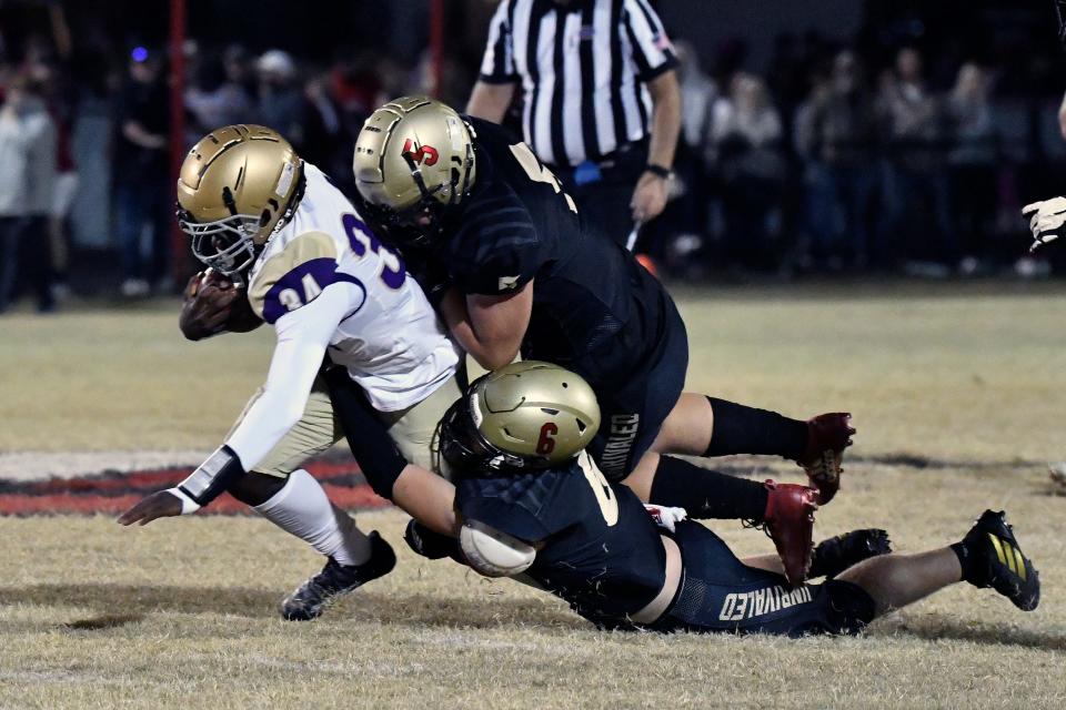 Male’s Chayce Burton (34) is dragged down by Bullitt East's Ryan Rayhill (6) and Isaiah Hare (5) during action of their game, Friday, Oct. 21 2022 in Mt. Washington Ky.