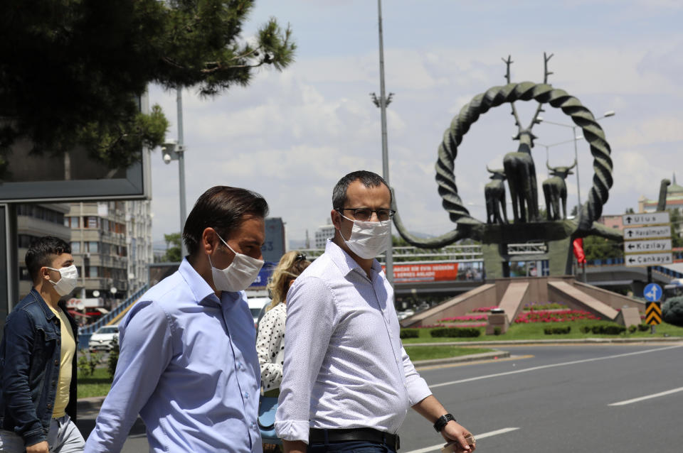 People wearing face masks to protect against the spread of coronavirus, walk in the city's historical part of Ulus, in Ankara, Turkey, Thursday, June 18, 2020. Turkish authorities have made the wearing of masks mandatory in three major cities to curb the spread of COVID-19 following an uptick in confirmed cases since the reopening of many businesses.(AP Photo/Burhan Ozbilici)