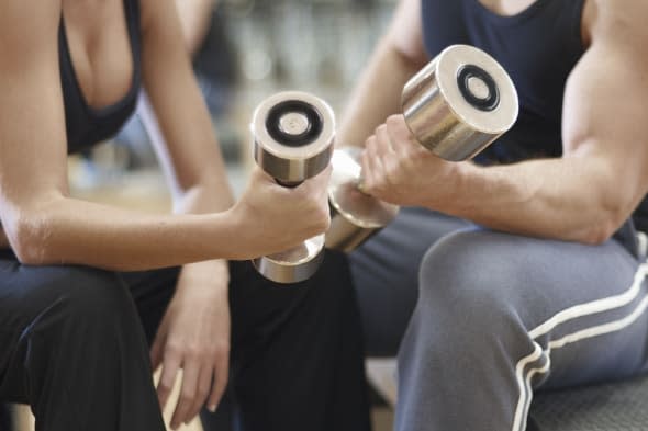 A man and woman working out at the gym with dumbbell weights