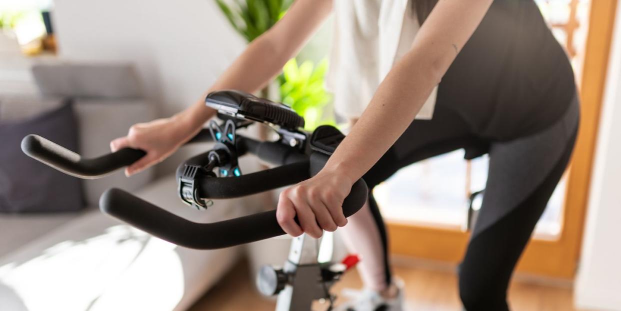 low section of woman training on exercise bike at home