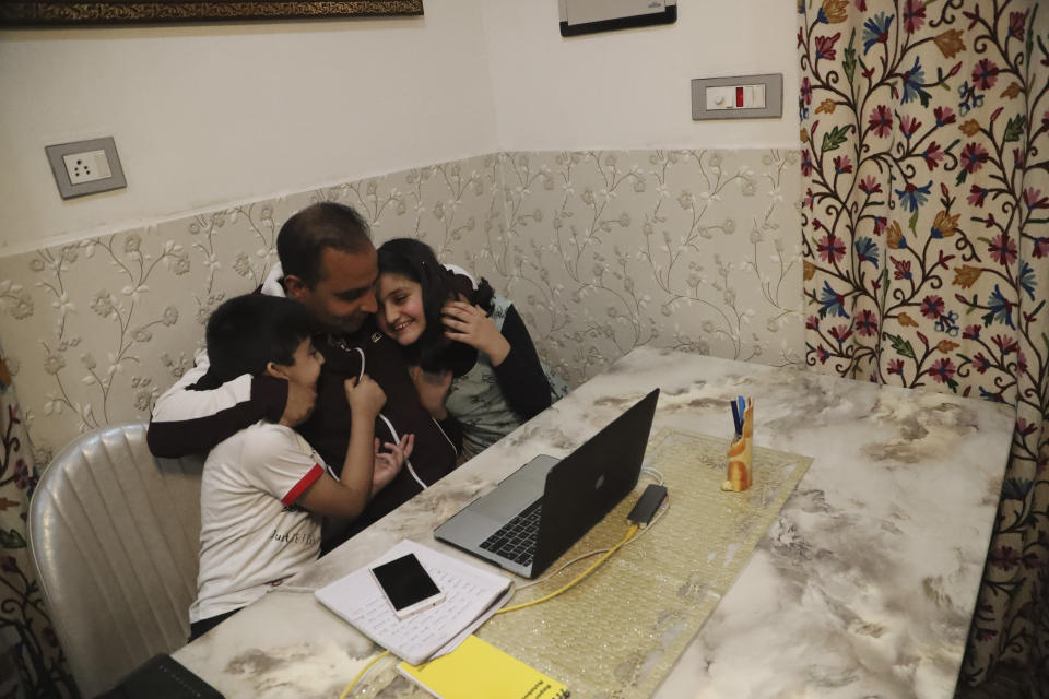 Associated Press photographer Mukhtar Khan hugs his children Mohammad Zehran, left, and Tazkiya, right, at his home in Srinagar, Indian controlled Kashmir, Tuesday, April 5, 2020, following the announcement that he was one of three AP photographers who won the Pulitzer Prize in Feature Photography for their coverage of the conflict in Kashmir and in Jammu, India. (AP Photo/Afnan Arif)