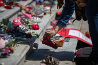<p>A woman places one of 215 pairs of children's shoes on the steps of the Vancouver Art Gallery as a memorial to the 215 children whose remains have been found buried at the site of a former residential school in Kamloops, in Vancouver, on Friday, May 28, 2021. Chief Rosanne Casimir of the Tk’emlups te Secwépemc First Nation said in a news release Thursday that the remains were confirmed last weekend with the help of a ground-penetrating radar specialist. THE CANADIAN PRESS/Darryl Dyck</p> 