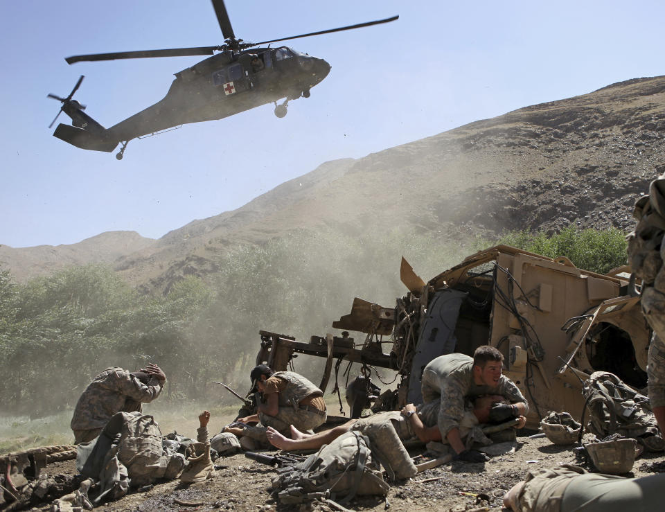 Spc. Paul Pickett, 22, of Minden La., right, of the U.S. Army's Apache Company, 2nd Battalion 87th Infantry Regiment, part of the 3rd Combat Brigade 10th Mountain Division based out of Fort Drum, N.Y., covers an injured U.S. soldier as a helicopter lands to evacuate the wounded after their armored vehicle hit an improvised explosive device in the Tangi Valley of Afghanistan's Wardak Province on Aug. 19, 2009. (AP Photo/David Goldman, File)