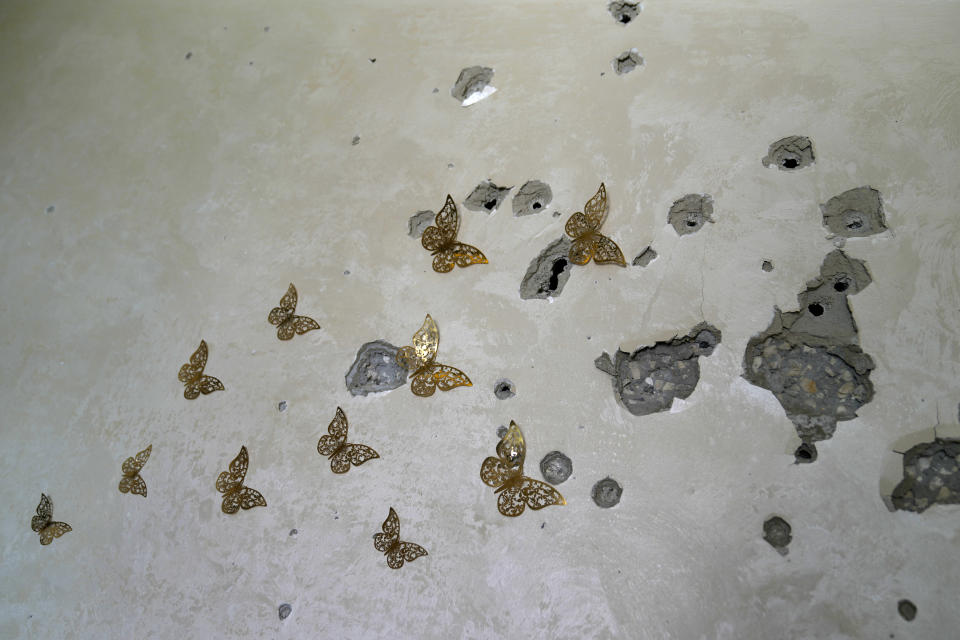 A bullet riddled wall with metal butterfly decorations is seen in the Nur Shams refugee camp in the West Bank on May 20, 2024. (AP Photo/Nasser Nasser)