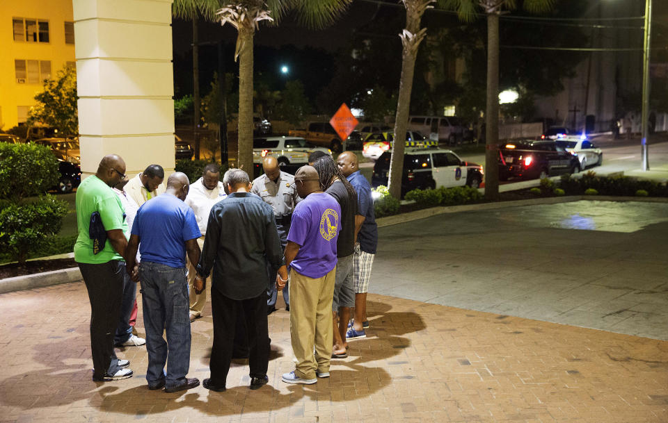 Worshippers gather to pray in a hotel parking lot across the street from the scene of the shooting. (AP Photo/David Goldman)