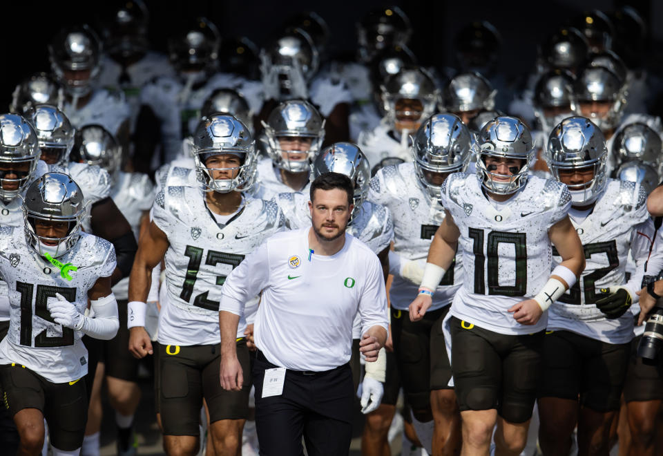 Nov 18, 2023; Tempe, Arizona, USA; Oregon Ducks head coach Dan Lanning (center) leads quarterback Bo Nix (10) and Ty Thompson (13) onto the field for the game against the Arizona State Sun Devils at Mountain America Stadium. Mandatory Credit: Mark J. Rebilas-USA TODAY Sports