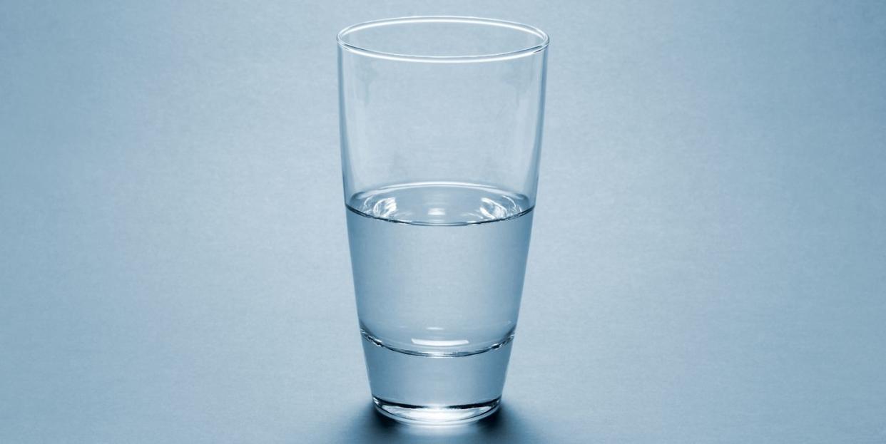 half full water glass over blue background