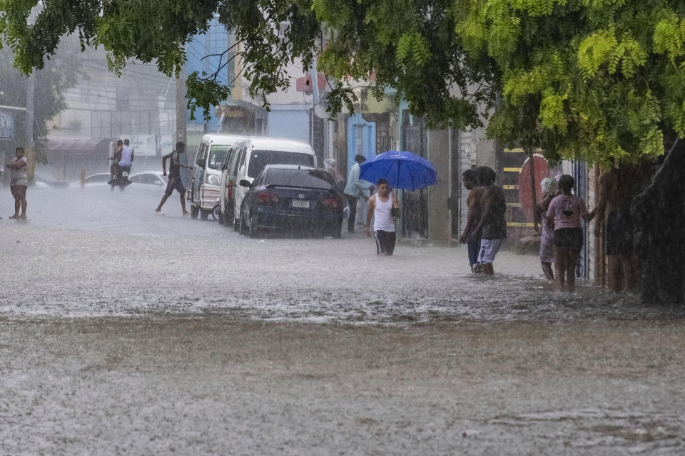 People walk through a street flooded by the rains of Tropical Storm Franklin in Santo Domingo, Dominican Republic, Tuesday, Aug. 22, 2023. (AP Photo/Ricardo Hernandez)