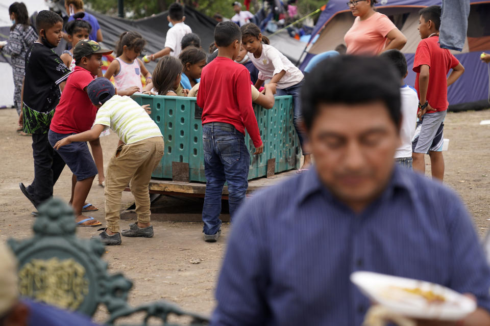 Jose Rodriguez, of Honduras, below right, sits as children play at a makeshift camp for migrants near the U.S.-Mexico border Thursday, May 13, 2021, in Reynosa, Mexico. Growing numbers of migrant families are making the heart-wrenching decision to separate from their children and send them into the U.S. alone. (AP Photo/Gregory Bull)