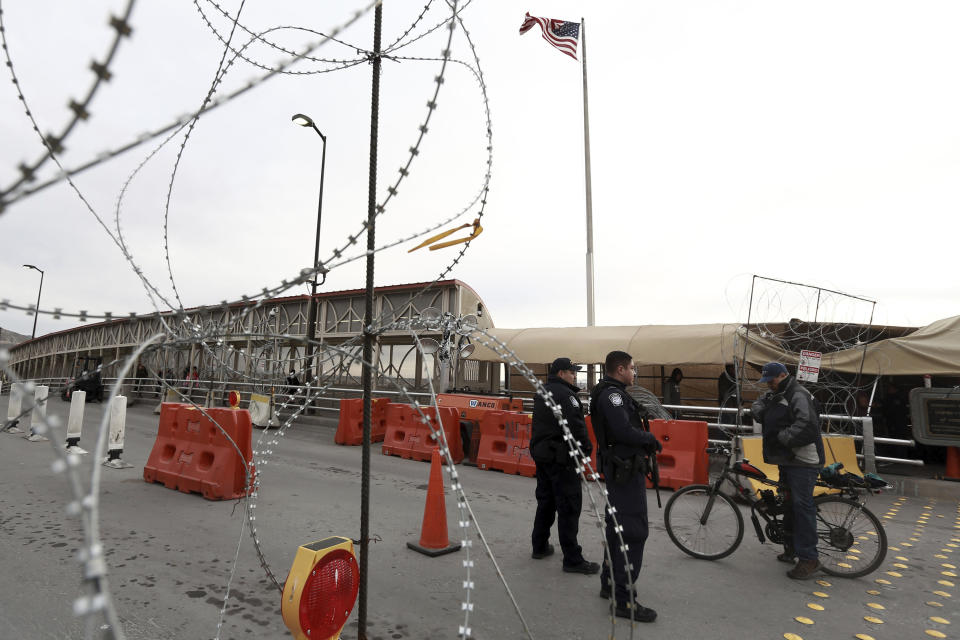 FILE - In this March 21, 2020, file photo, U.S. border agents question a man traveling on a bicycle on an international bridge at the U.S-Mexico border that joins Ciudad Juarez and El Paso, Texas. Mexico and the U.S. are restricting travel over their busy shared border as they try to control the spread of the coronavirus pandemic. The state of California is freeing up to $28 million to help asylum-seekers released in the U.S. with notices to appear in court with hotels, medical screenings, and transportation. California's generosity is a stark contrast to Arizona and Texas, where border state officials have challenged and sharply criticized President Joe Biden's immigration policies. Arizona and Texas have emerged as top challengers to Biden's court policies, a role that California proudly assumed during Trump's presidency. (AP Photo/Christian Chavez, File)