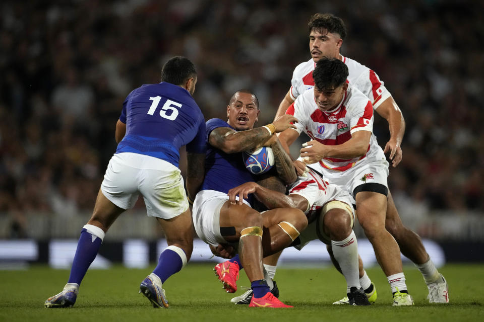 Samoa's Ed Fidow, centre, is tackled by Japan's players during the Rugby World Cup Pool D match between Japan and Samoa, at the Stadium de Toulouse in Toulouse, France, Thursday, Sept. 28, 2023. (AP Photo/Christophe Ena)