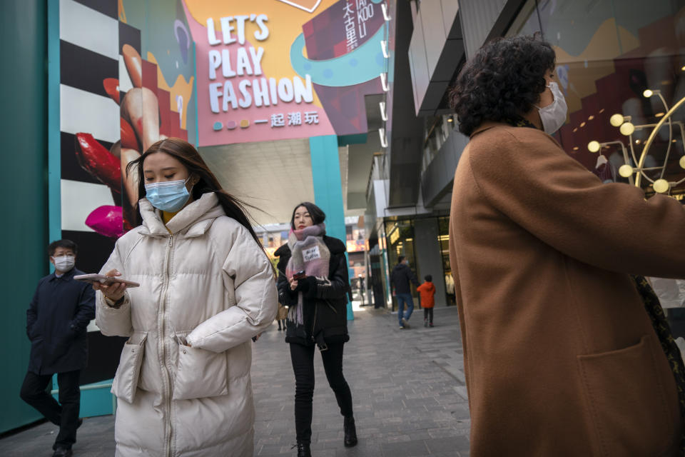 People wearing face masks to protect against the coronavirus walk at an outdoor shopping area in Beijing, Saturday, Nov. 28, 2020. (AP Photo/Mark Schiefelbein)