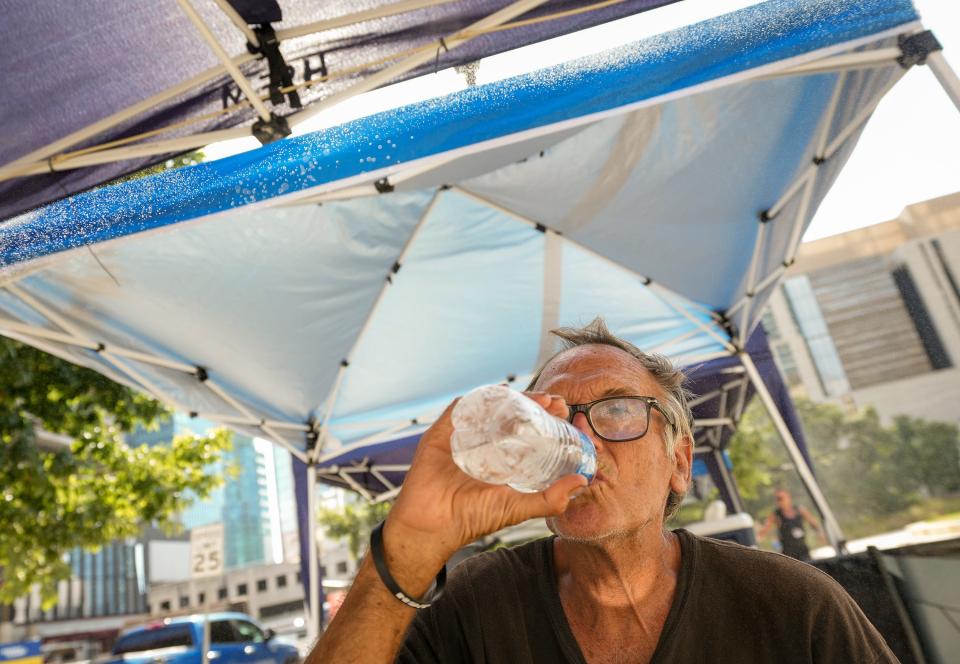 Ron Zobel drinks cold water at a misting station at Republic Square Park in downtown Austin on July 31, when the temperature was 104 degrees. The city set up misting canopies and provided cold water at the square.