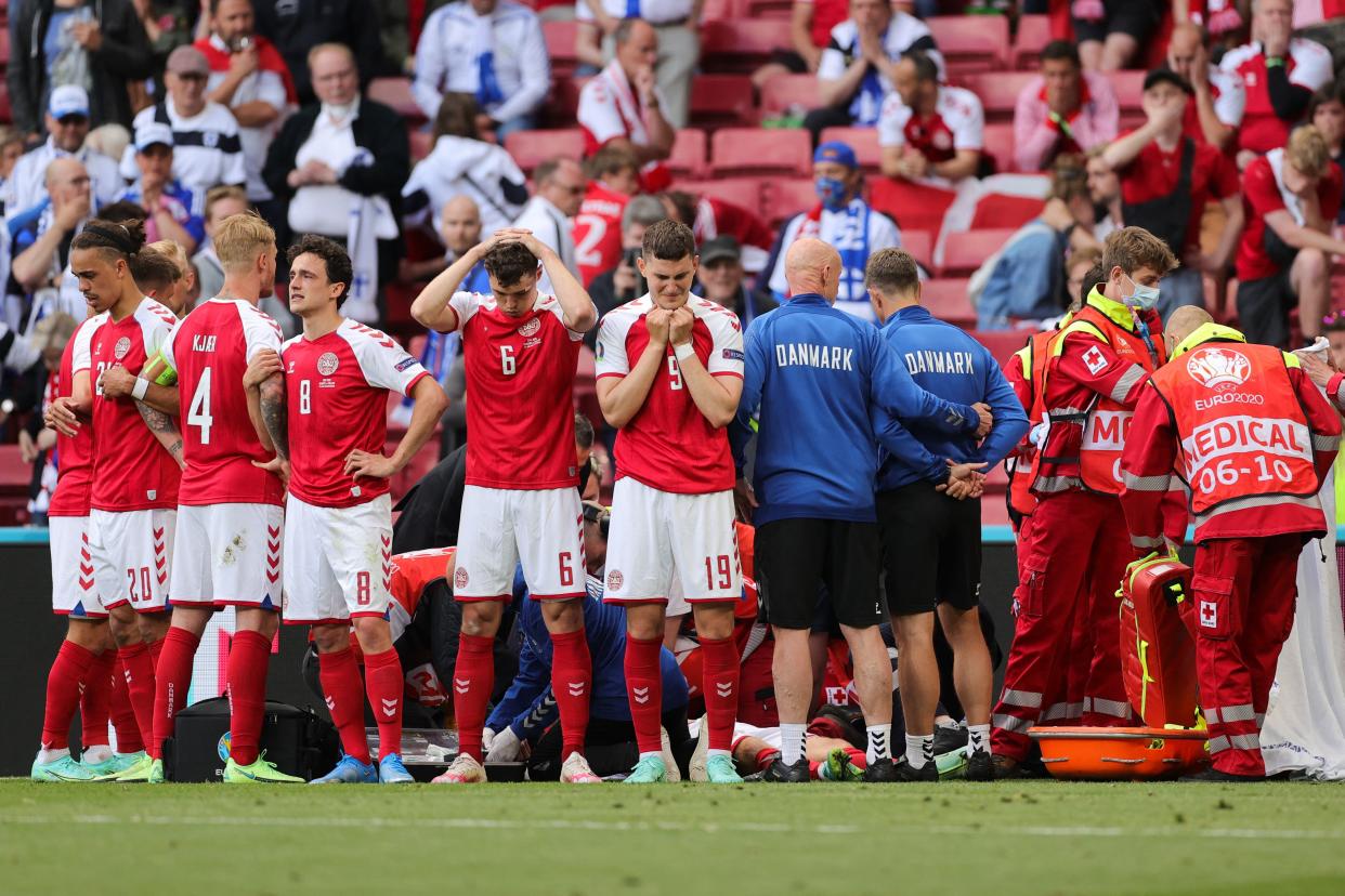 Denmark players form a circle around Christian Eriksen as paramedics attend to him on the field. (Photo by Friedemann Vogel / POOL / AFP via Getty Images)