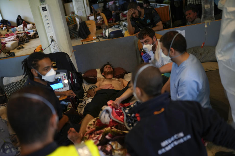 A Red Cross health worker calls an ambulance to transfer a man on hunger strike to a hospital as he occupies with others a big room of the ULB Francophone university in Brussels, Tuesday, June 29, 2021. More than two hundreds of migrants without official papers and who have been occupying a church and two buildings of two Brussels universities since last February, began a hunger strike on 23 May to draw the attention of Brussels authorities to their plight. (AP Photo/Francisco Seco)
