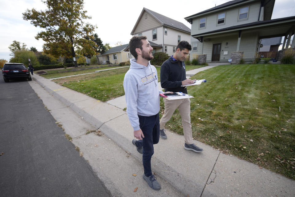 Vote canvassers Zach Martinez, front, and Joshua Posner check their itinerary while making visits to homeowners along Ash Street Tuesday, Nov. 1, 2022, in northeast Denver. Coloradoans are taking the state's housing crisis into their own hands by turning to local and statewide ballot measures intended to quell the soaring costs. (AP Photo/David Zalubowski)