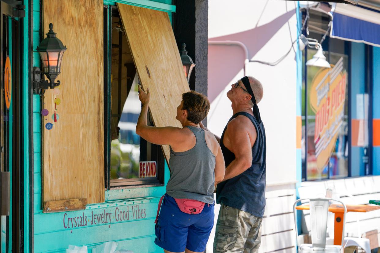 Lisa Bromfield and Mike Sernett work to place a sheet of plywood on the front windows of a store in downtown Gulfport in preparation for the arrival of Hurricane Ian, Monday, Sept. 26, 2022 in South Pasadena, Fla. 