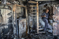 Avi Korkas, a municipality worker, examines the damages of a municipality office in charge of an outdoor food market, that was torched after a night of violence between Israeli Arab protesters and Israeli police in the mixed Arab-Jewish town of Lod, central Israel, Tuesday, May 11, 2021. (AP Photo/Heidi Levine)