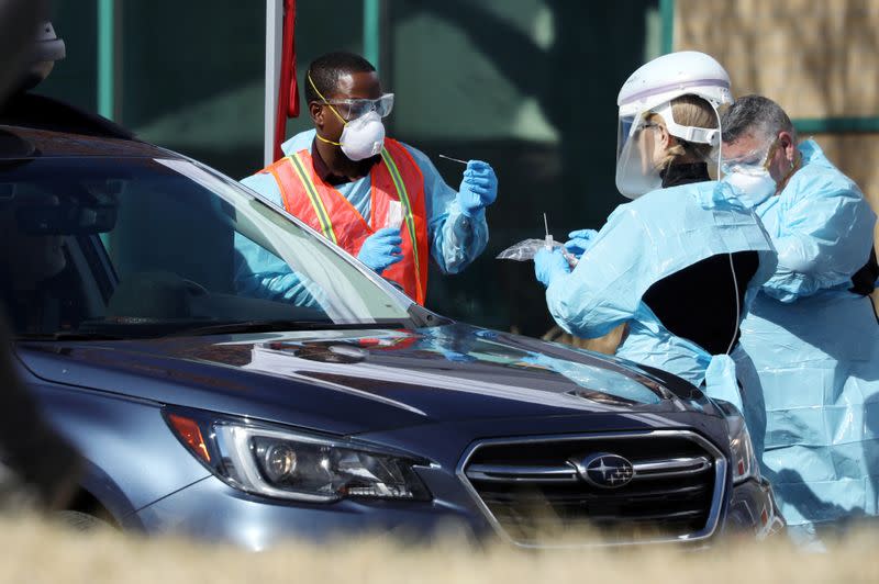 Health care workers test people at a drive-thru testing station run by the state health department, for people who suspect they have novel coronavirus, in Denver, Colorado