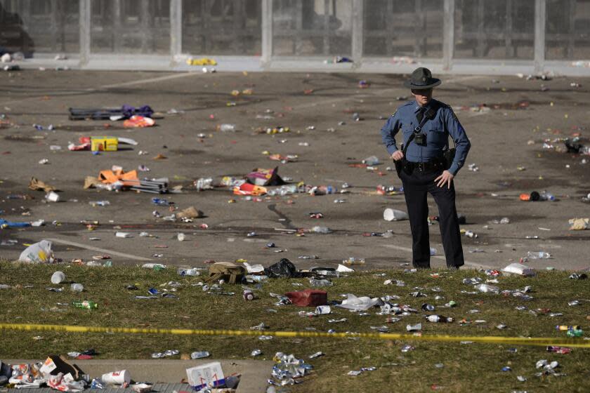 A law enforcement officer looks around the scene following a shooting at the Kansas City Chiefs NFL football Super Bowl celebration in Kansas City, Mo., Wednesday, Feb. 14, 2024. Multiple people were injured, a fire official said.(AP Photo/Charlie Riedel)