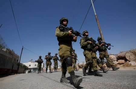 FILE PHOTO: Israeli soldiers patrol following a protest by Palestinians against closure of a road south of Hebron