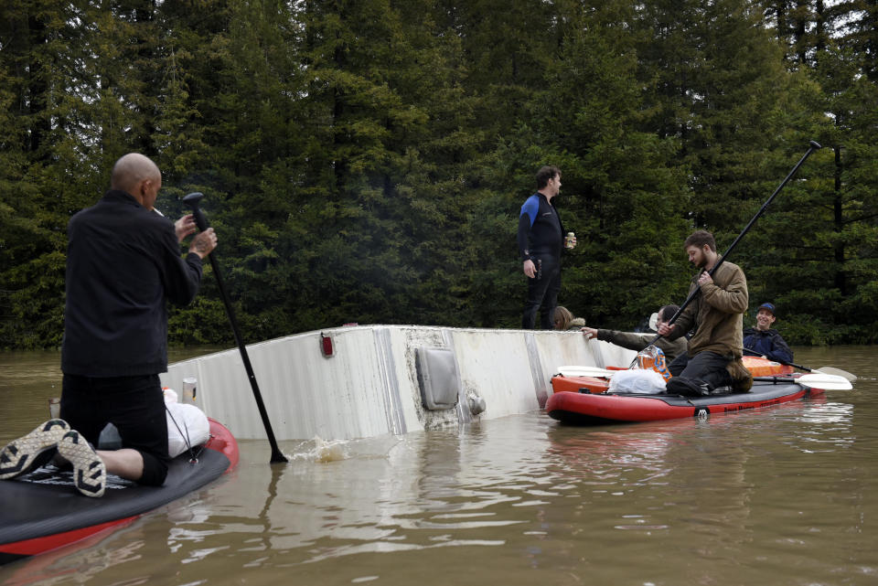 People gather on a partially submerged RV in the flood waters of the Russian River in Forestville, north of San Francisco, Feb. 27, 2019. The rain that swamped the area came from a storm system that also dumped heavy snow in the mountains of California and Nevada and in Washington state, Oregon, Idaho and Montana. (Photo: Michael Short/AP)