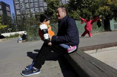 A 56-year-old man plays with his 2-year-old granddaughter at a residential community in Beijing, China, October 30, 2015. REUTERS/Jason Lee/Files