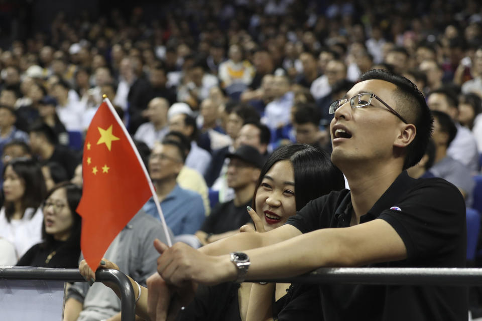 Chinese fans with a Chinese flag watch a preseason NBA basketball game between the Brooklyn Nets and Los Angeles Lakers at the Mercedes Benz Arena in Shanghai, China, Thursday, Oct. 10, 2019. (AP Photo)