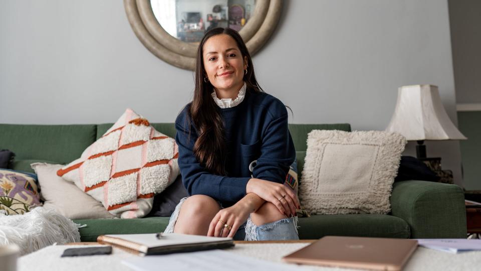 Hattie MacAndrews smiling on a sofa