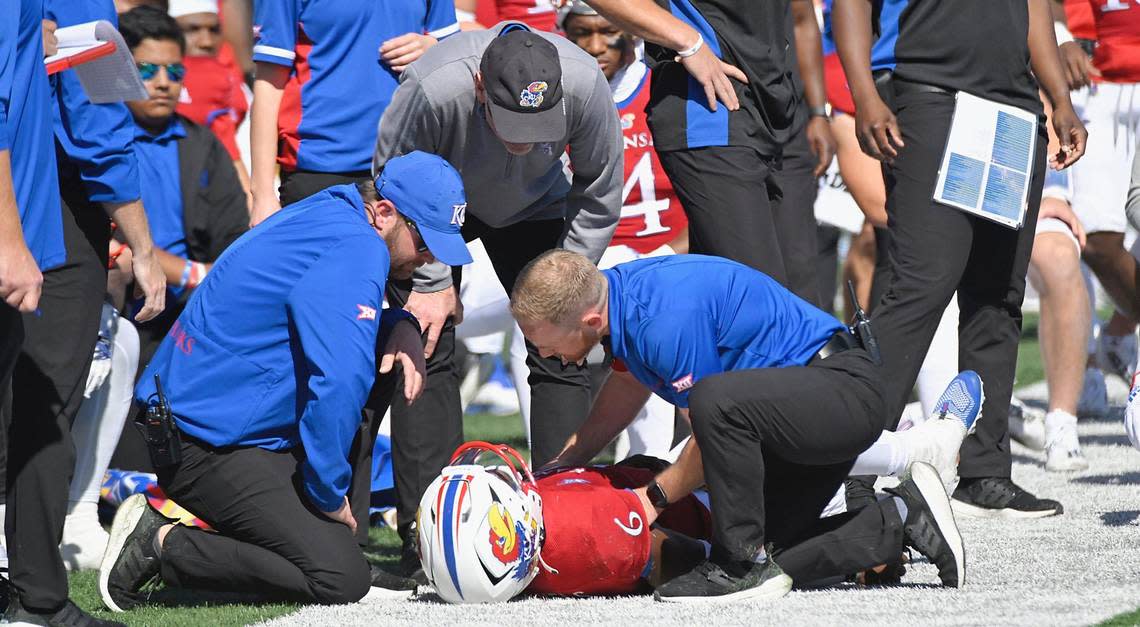 Kansas Jayhawks head coach, Lance Liepold, with black hat, checks on quarterback Jalon Daniels after he was injured late in the first half while playing TCU Saturday, October 8, 2022, at David Booth Memorial Stadium in Lawrence, Kansas.