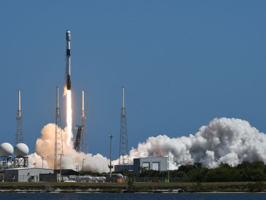 The launch of a SpaceX rocket just barely off the ground surrounded by smoke