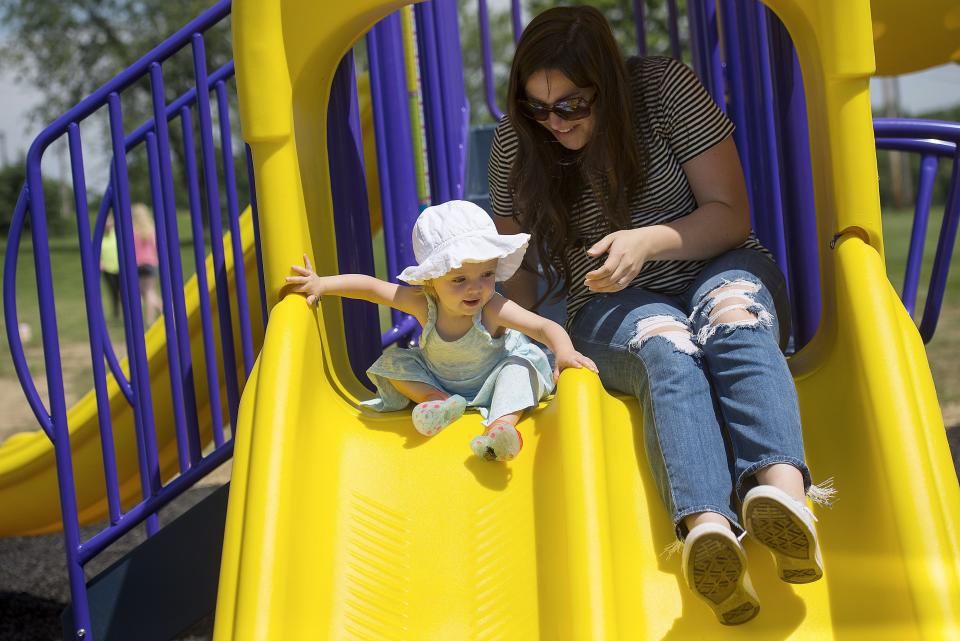 Elaina Elder, of Economy Borough, helps her daughter, Annabelle, 1, go down a small slide on June 16, 2018, at the playground at Economy Borough Municipal Park. Members of the Economy Borough Recreation Board set up games alongside the playground and provided water, snow cones and popcorn after a morning ribbon-cutting ceremony.
