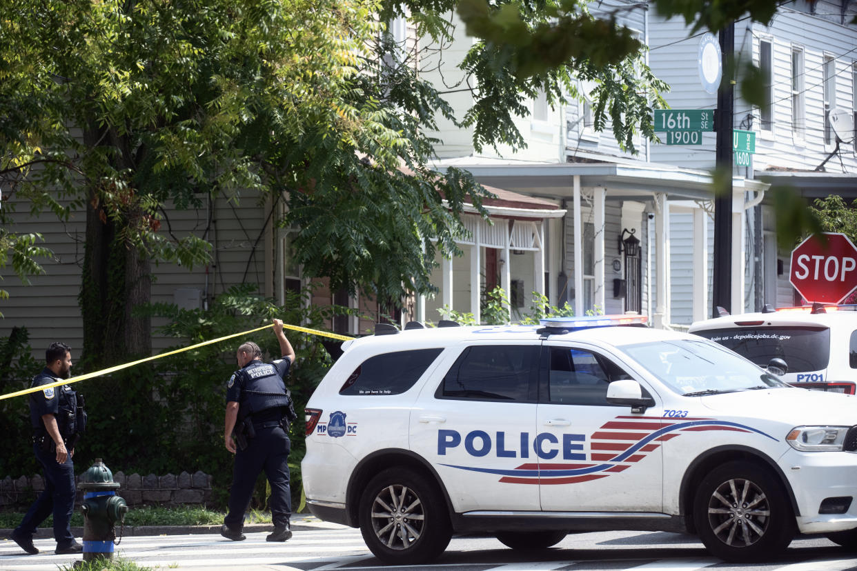 A police vehicle and officers are seen on a residential street.