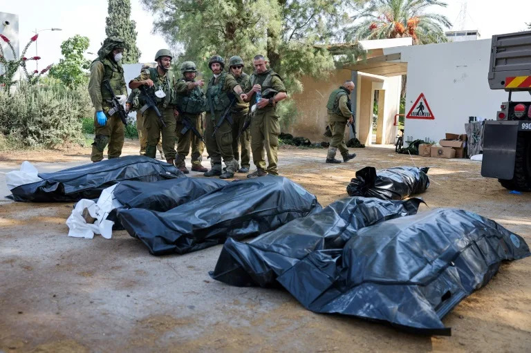 Israeli soldiers prepare to remove the bodies of compatriots killed by Palestinian militants in the kibbutz of Kfar Aza where more than 100 civilians are believed to have been massacred (JACK GUEZ)