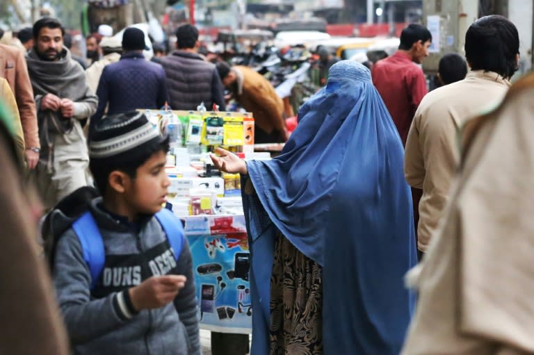 Une femme en burqa fait la manche sur un marché de Jalalabad, en Afghanistan, le 1er février 2023 (Shafiullah KAKAR)
