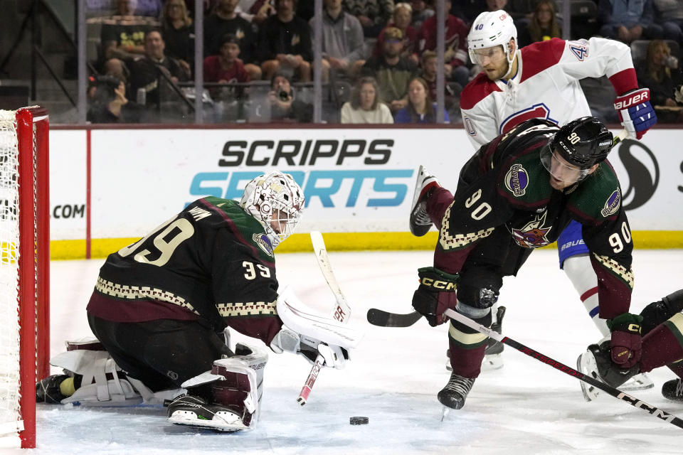 Arizona Coyotes goaltender Connor Ingram (39) makes a save on a shot by Montreal Canadiens right wing Joel Armia (40) as Coyotes defenseman J.J. Moser (90) skates past during the second period of an NHL hockey game Thursday, Nov. 2, 2023, in Tempe, Ariz. (AP Photo/Ross D. Franklin)